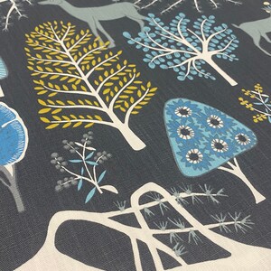 May include: A dark blue fabric with a white, blue, and yellow stylized forest design. The design features trees, deer, and flowers.