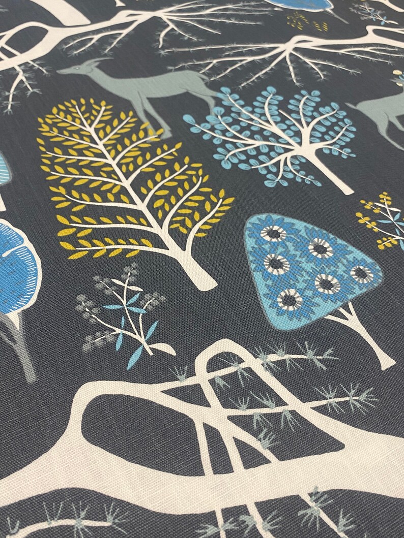 May include: A dark blue fabric with a white, blue, and yellow stylized forest design. The design features trees, deer, and flowers.