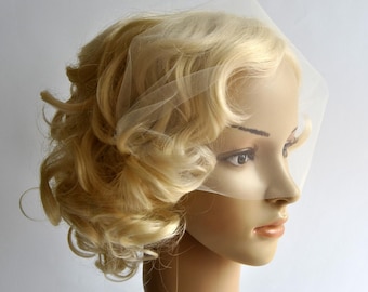 May include: A white tulle veil with a square shape, worn on a blonde wig. The veil is sheer and delicate, and it covers the top of the head and part of the face.