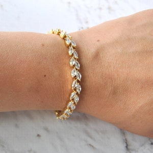 K&ouml;nnte beinhalten: Ein goldenes Armband mit einer Reihe von klaren birnenf&ouml;rmigen Steinen.