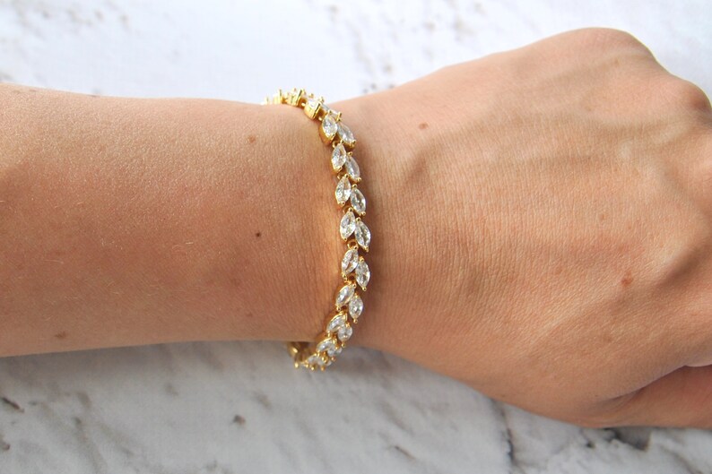 K&ouml;nnte beinhalten: Ein goldenes Armband mit einer Reihe von klaren birnenf&ouml;rmigen Steinen.