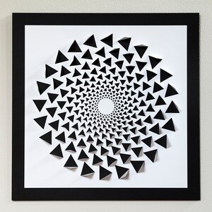 May include: A black and white paper art piece featuring a spiral design made of overlapping triangles. The triangles are arranged in a circular pattern, creating a sense of depth and movement.