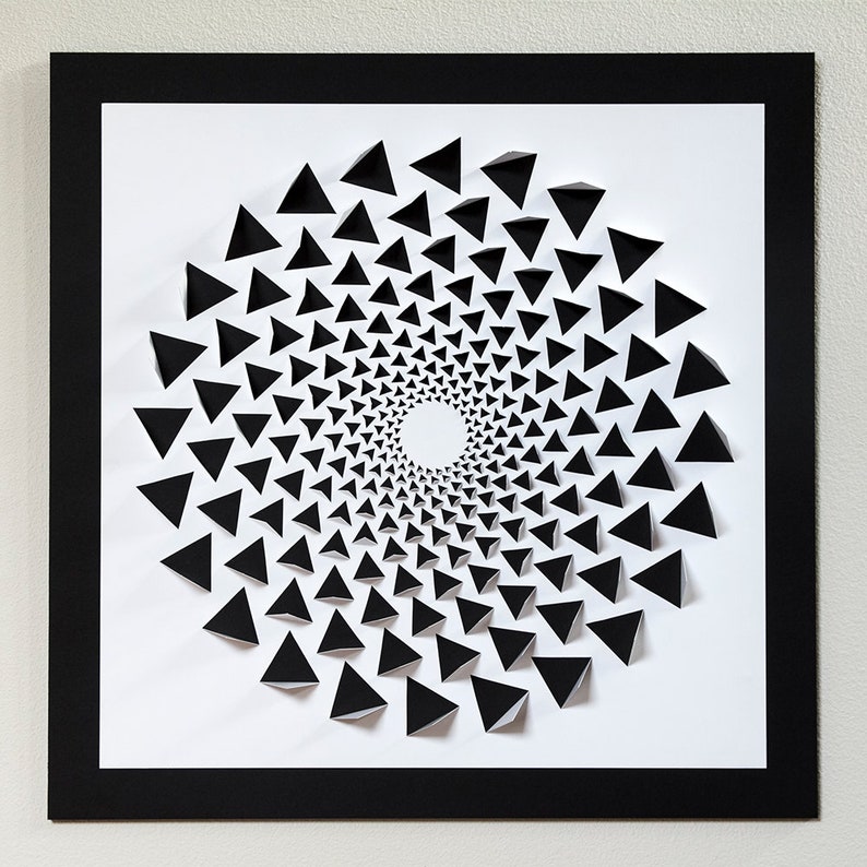 May include: A black and white paper art piece featuring a spiral design made of overlapping triangles. The triangles are arranged in a circular pattern, creating a sense of depth and movement.