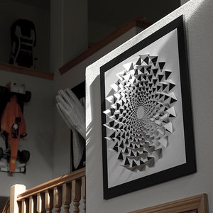 May include: A framed black and white geometric art print with a spiral design. The print is hanging on a white wall.
