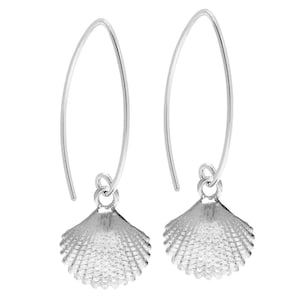May include: Silver dangle earrings with a detailed seashell charm. The earrings are made of a thin silver wire and have a simple, elegant design.