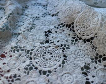 May include: White crochet lace fabric with a delicate pattern of circles and swirls.