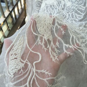 Puede incluir: Tela blanca transparente con un delicado bordado blanco de dise&ntilde;o de rama de &aacute;rbol.