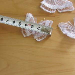 May include: White lace butterfly appliques with a measuring tape showing 3 inches. These delicate appliques are perfect for adding a touch of elegance to any project.
