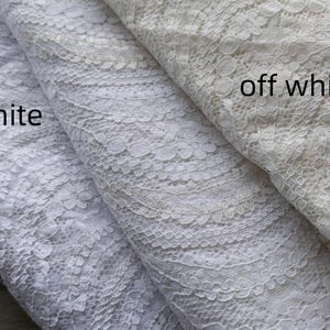 May include: Close-up of three folded fabrics with intricate lace patterns. The fabrics are in shades of white, labeled "pure white" and "off white". The lace design features floral and geometric elements, creating a delicate texture.