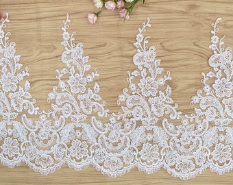 May include: White lace trim with a delicate floral pattern. The lace has a scalloped edge and is perfect for adding a touch of elegance to any project.