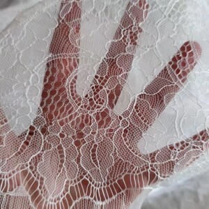 May include: White lace fabric with a delicate floral pattern. The lace is soft and sheer, and it would be perfect for a variety of crafting projects.
