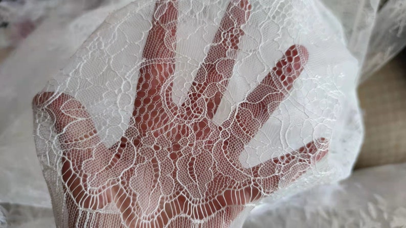 May include: White lace fabric with a delicate floral pattern. The lace is soft and sheer, and it would be perfect for a variety of crafting projects.