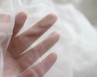 May include: White mesh fabric with a fine, even weave. The fabric is soft and delicate, with a slightly sheer appearance.