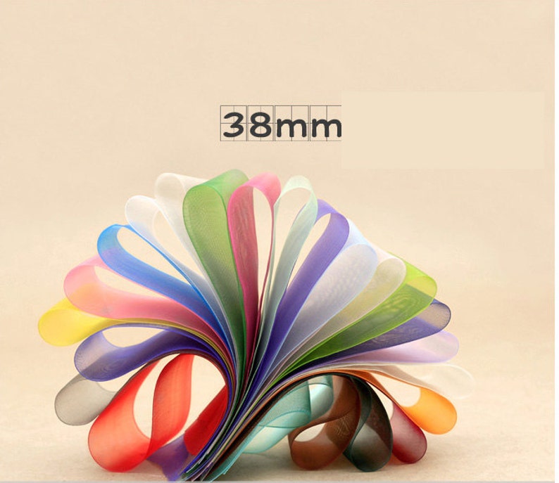 May include: A collection of 12 colorful sheer ribbon rolls, each measuring 38mm wide. The ribbons are arranged in a fan shape, showcasing a variety of colors, including yellow, orange, red, pink, blue, green, and white.
