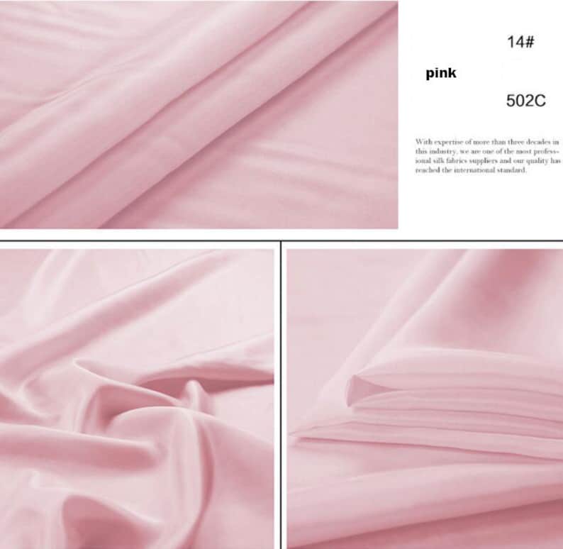 May include: A close-up of a soft, pink fabric. The fabric is smooth and silky. The fabric is folded in half and the edges are visible. The fabric is a light pink color. 14# pink 502C