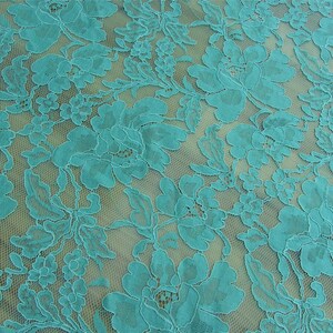 May include: Teal lace fabric with a floral pattern. The lace is delicate and has a soft, flowing texture.