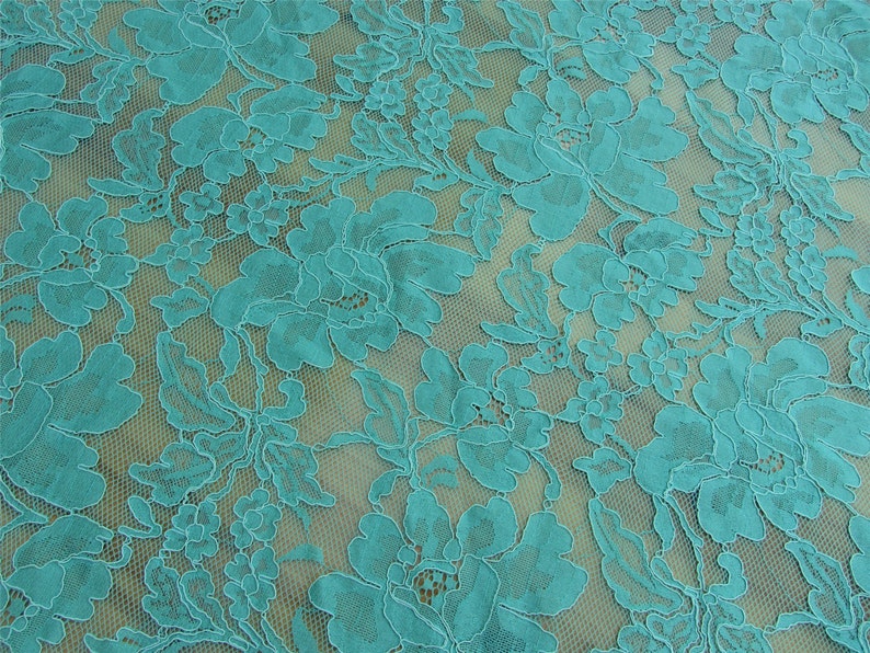 May include: Teal lace fabric with a floral pattern. The lace is delicate and has a soft, flowing texture.