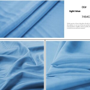 May include: Close-up of a light blue fabric with a smooth, silky texture. The fabric is folded and draped, showcasing its flowy nature. The color code 7454C is visible in the image.