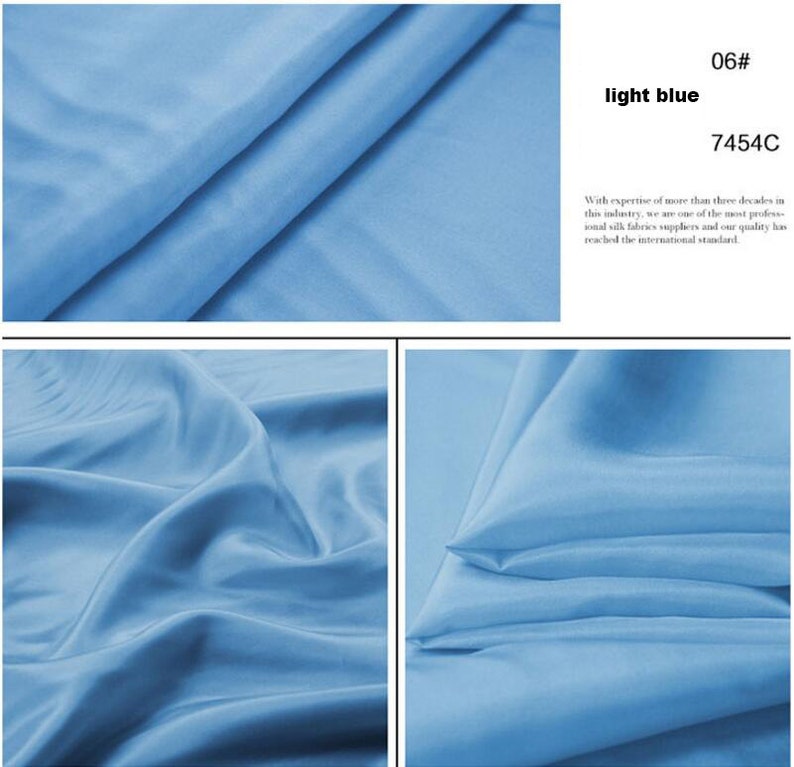 May include: Close-up of a light blue fabric with a smooth, silky texture. The fabric is folded and draped, showcasing its flowy nature. The color code 7454C is visible in the image.