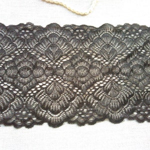 Pode incluir: Close-up de uma renda preta com borda ondulada. A renda apresenta um padr&atilde;o floral repetido com trabalho aberto detalhado. Ideal para costura, artesanato ou para adicionar elementos decorativos a roupas ou projetos de decora&ccedil;&atilde;o.