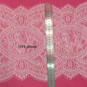 Puede incluir: Borde de encaje blanco con un borde festoneado. El encaje tiene aproximadamente 30 centímetros de ancho.