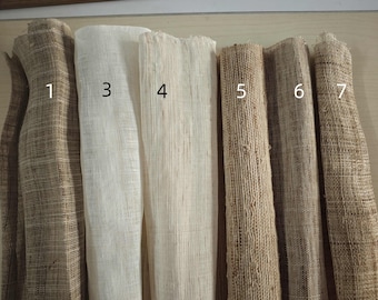 Puede incluir: Una colección de siete rollos de tela tejida en varios tonos neutros. Las telas varían en color desde beige claro hasta marrón oscuro, con texturas visibles y diferentes tejidos. Los rollos están numerados del 1 al 7.
