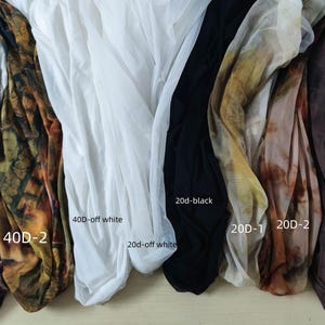 Peut inclure: Assortiment de tissus transparents de diff&eacute;rentes couleurs et motifs. Comprend des imprim&eacute;s animaliers, des motifs abstraits, du blanc, du noir et du marron. Chaque tissu est &eacute;tiquet&eacute; avec son denier et sa couleur, comme "20d-black".