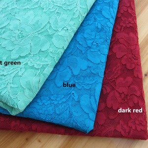 May include: Three pieces of lace fabric in different colors: light green, blue, and dark red. The lace has a floral pattern.