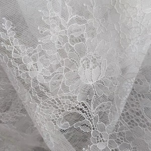 May include: White lace fabric with a floral pattern. The lace is delicate and intricate, with a soft, flowing texture.