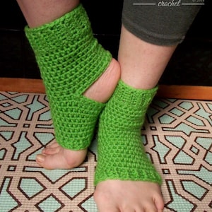 Puede incluir: Un par de calentadores de tobillo de crochet verde con una abertura para los dedos. Los calentadores se usan en los pies de una persona y se muestran en una alfombra estampada.