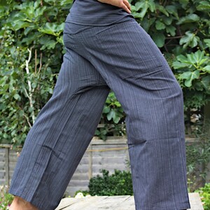 May include: A pair of gray striped pants with a loose fit and a wide leg. The pants have a drawstring waistband and two pockets on the front.