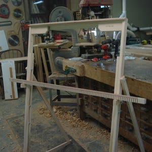 Op de afbeelding: Een houten weefraam met een houten kettingboom en een houten heden. De weefgetouw is opgesteld op een houten tafel met laden. De weefgetouw is gemaakt van natuurlijk hout en heeft een eenvoudig ontwerp.