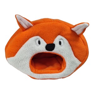 May include: A novelty pet bed in the shape of a fox's head. The bed is orange with white and black details, including a fox face with an open mouth. The bed is designed to provide a cosy space for a small pet.