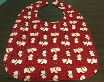 May include: A red baby bib with a repeating pattern of white polar bears wearing scarves. The bib has a curved shape with a neck opening and a Velcro closure.