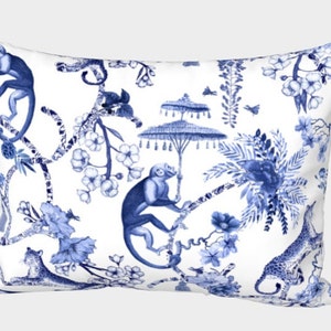 May include: A white pillow with a blue and white pattern of monkeys, flowers, and palm trees. The pattern is reminiscent of traditional Chinese porcelain.