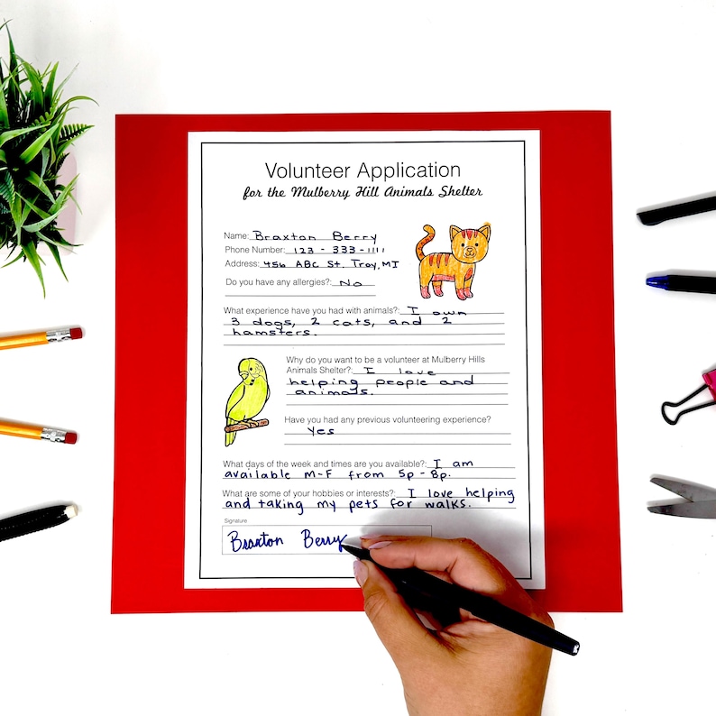 May include: A white Volunteer Application form for the Mulberry Hill Animals Shelter on a red background. The form includes handwritten text, a cartoon orange cat, and a yellow bird illustration. A hand holds a black pen, signing the document.