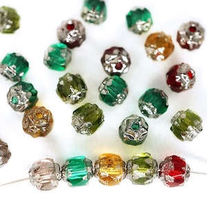 Puede incluir: Surtido de cuentas de vidrio facetadas en varios colores, incluyendo verde, rojo y dorado. Las cuentas tienen un ribete de metal plateado y están enhebradas en un alambre.