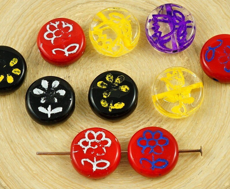 May include: Assortment of round glass beads with various floral designs. The beads are in red, black, yellow, and purple with white accents.