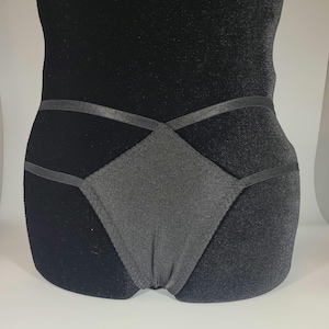 May include: Black underwear with a criss-cross design and a satin-like finish.