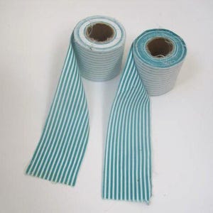 May include: Two rolls of striped ribbon in teal and white. The ribbon is unrolled, showing the striped pattern. The rolls are made of a fabric material and are on a white background.