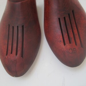 K&ouml;nnte beinhalten: Ein Paar braune Holzschuhspanner mit geriffeltem Design. Die Schuhspanner sind mit den Zahlen "9" und "10" gekennzeichnet.
