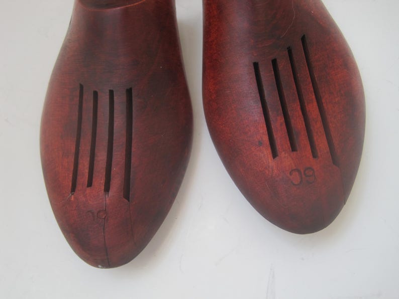K&ouml;nnte beinhalten: Ein Paar braune Holzschuhspanner mit geriffeltem Design. Die Schuhspanner sind mit den Zahlen "9" und "10" gekennzeichnet.