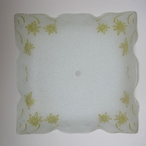 May include: A white frosted glass ceiling light fixture with a square shape and scalloped edges. The fixture has a floral design in a light green color.