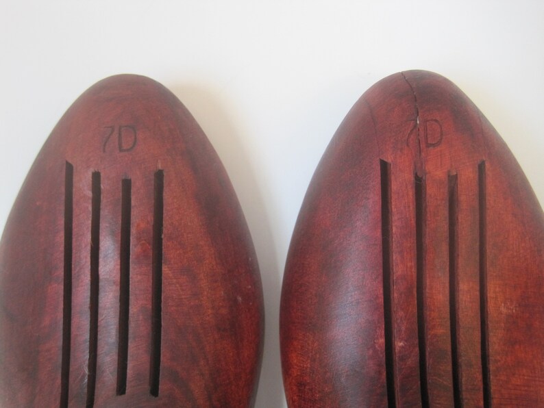 Puede incluir: Un par de estiradores de zapatos de madera marr&oacute;n con un dise&ntilde;o acanalado. Los estiradores de zapatos est&aacute;n etiquetados como "7D" y "7D".