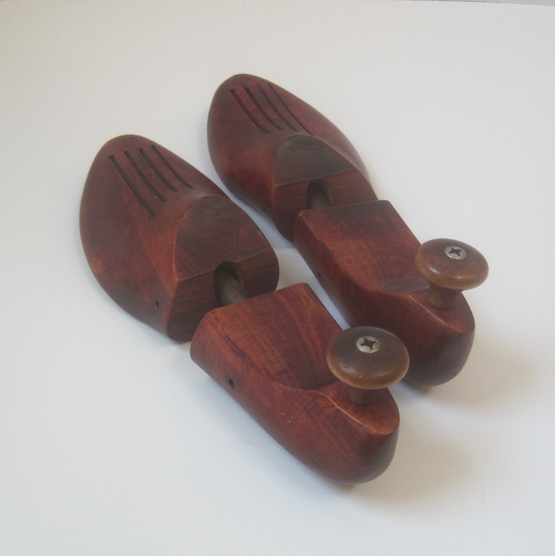 Puede incluir: Un par de hormas de zapatos de madera con un acabado marr&oacute;n rojizo. Las hormas tienen un pomo en el extremo de cada pieza.