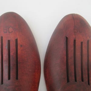 K&ouml;nnte beinhalten: Ein Paar braune Holzschuhspanner mit geriffeltem Design und dem Buchstaben "C" auf der Oberseite.