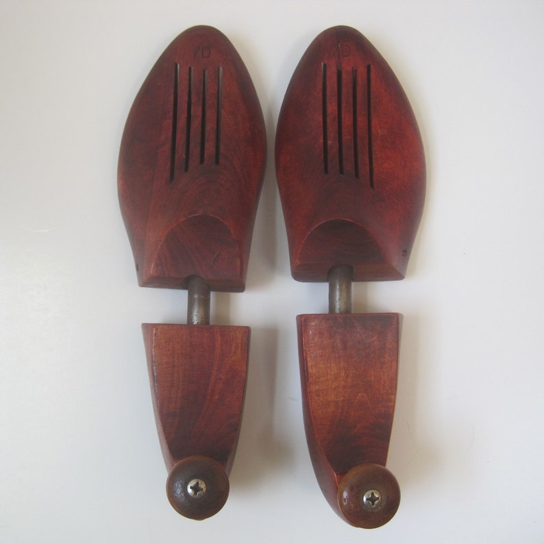 Puede incluir: Un par de hormas de zapatos de madera con un acabado marr&oacute;n rojizo. Las hormas tienen una varilla de metal que se extiende desde la parte superior hasta la parte inferior de la horma. Las hormas est&aacute;n dise&ntilde;adas para ayudar a mantener la forma de los zapatos.