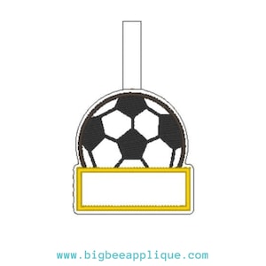 Könnte beinhalten: Ein weißer und schwarzer Fußball mit einem gelben rechteckigen Etikett zur Personalisierung. Das Etikett ist leer.