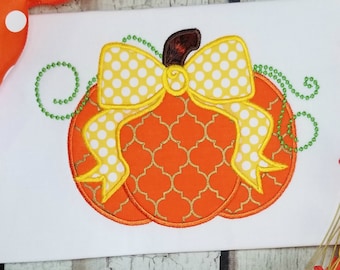 May include: A bright orange pumpkin with a yellow polka dot bow and green vines. The pumpkin has a gold and orange geometric pattern.