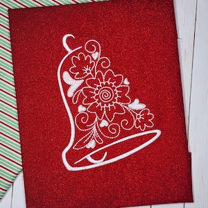 May include: White embroidered bell with floral designs on a red background.